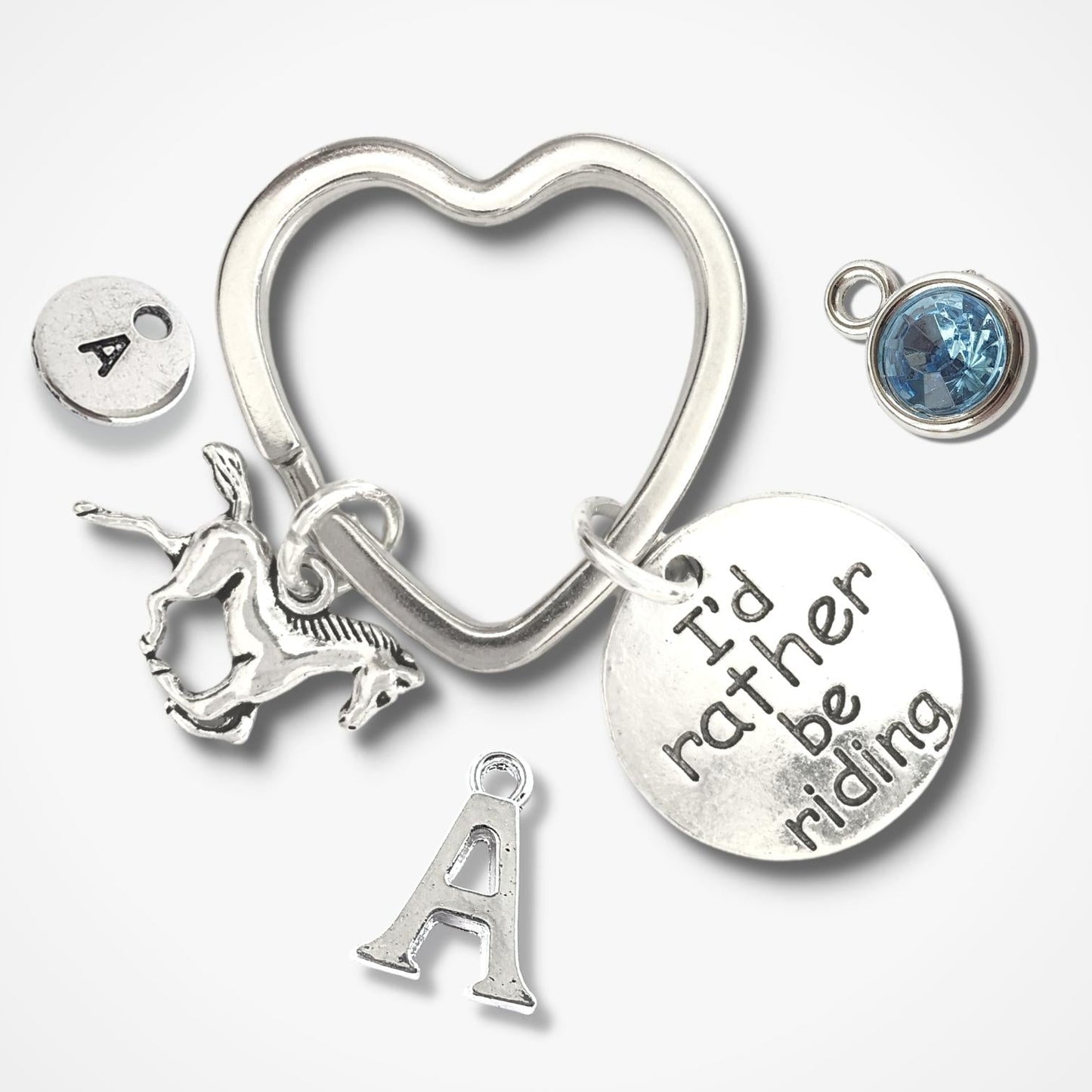 Silver heart-shaped keychain with various charms on a white background