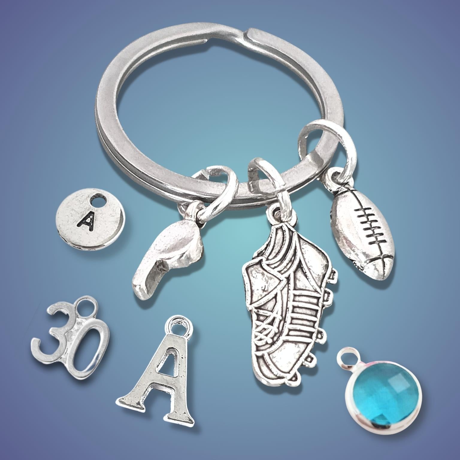 Silver keychain with various rugby themed charms on a blue gradient background