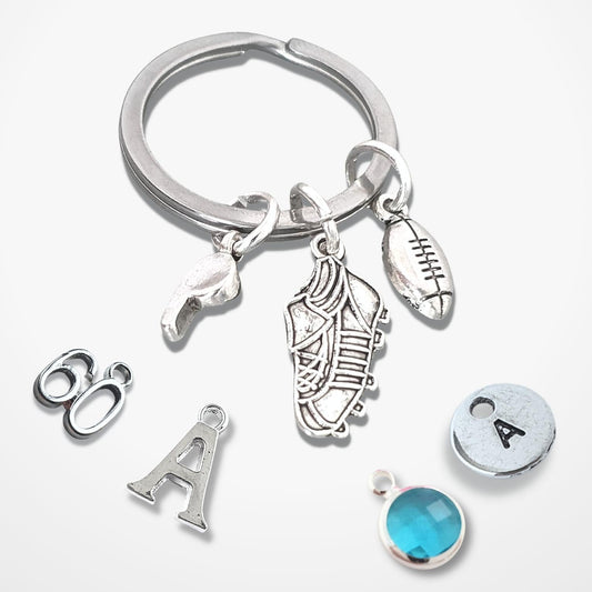 Silver keychain with various rugby themed charms on a white background