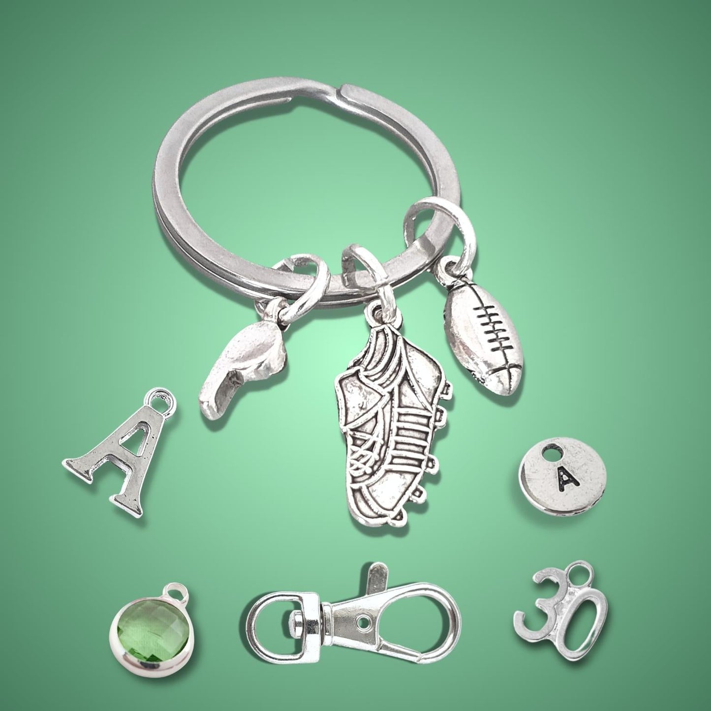 Silver keychain with various rugby themed charms on a green background