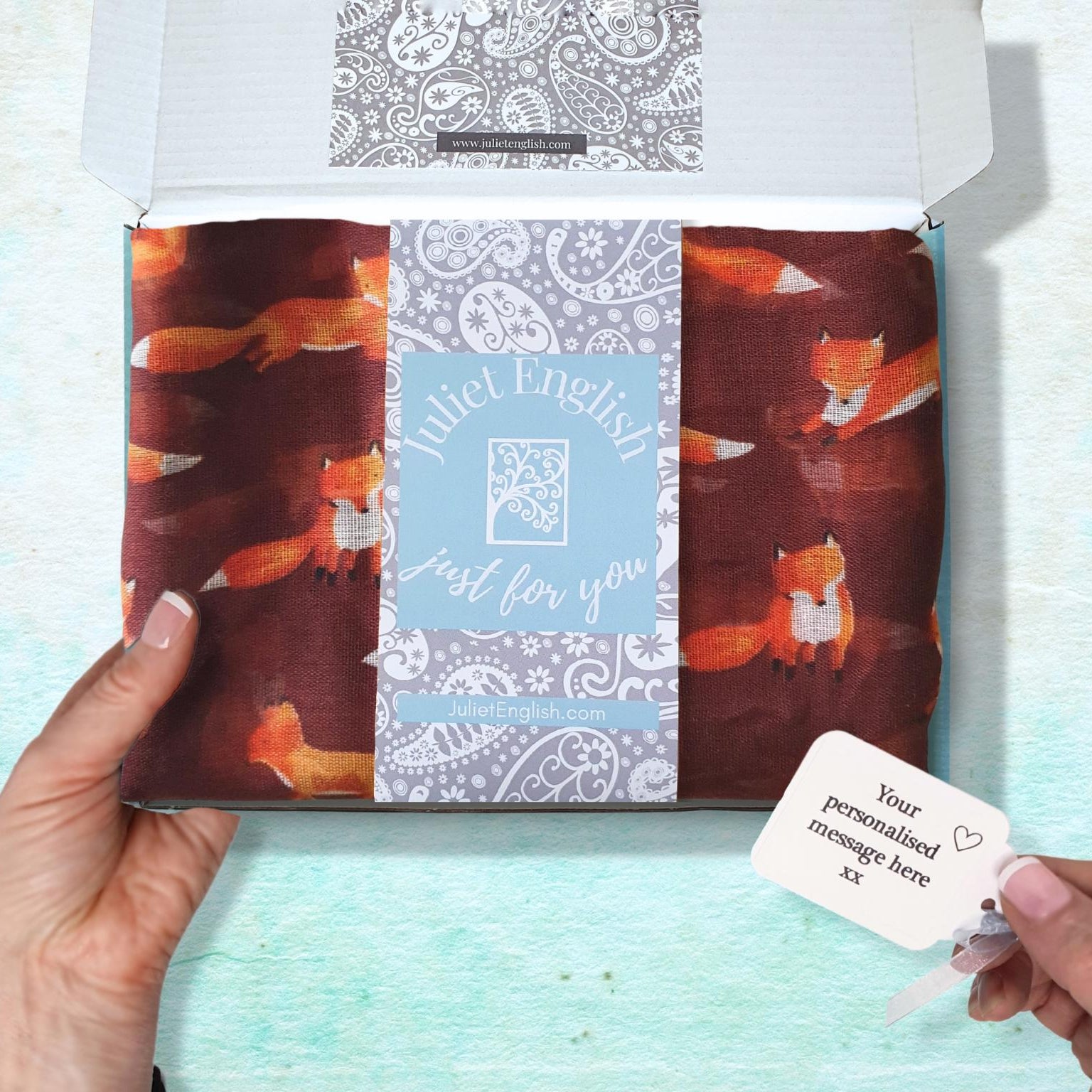Packaged scarf with fox pattern and personalised message card on a light blue background