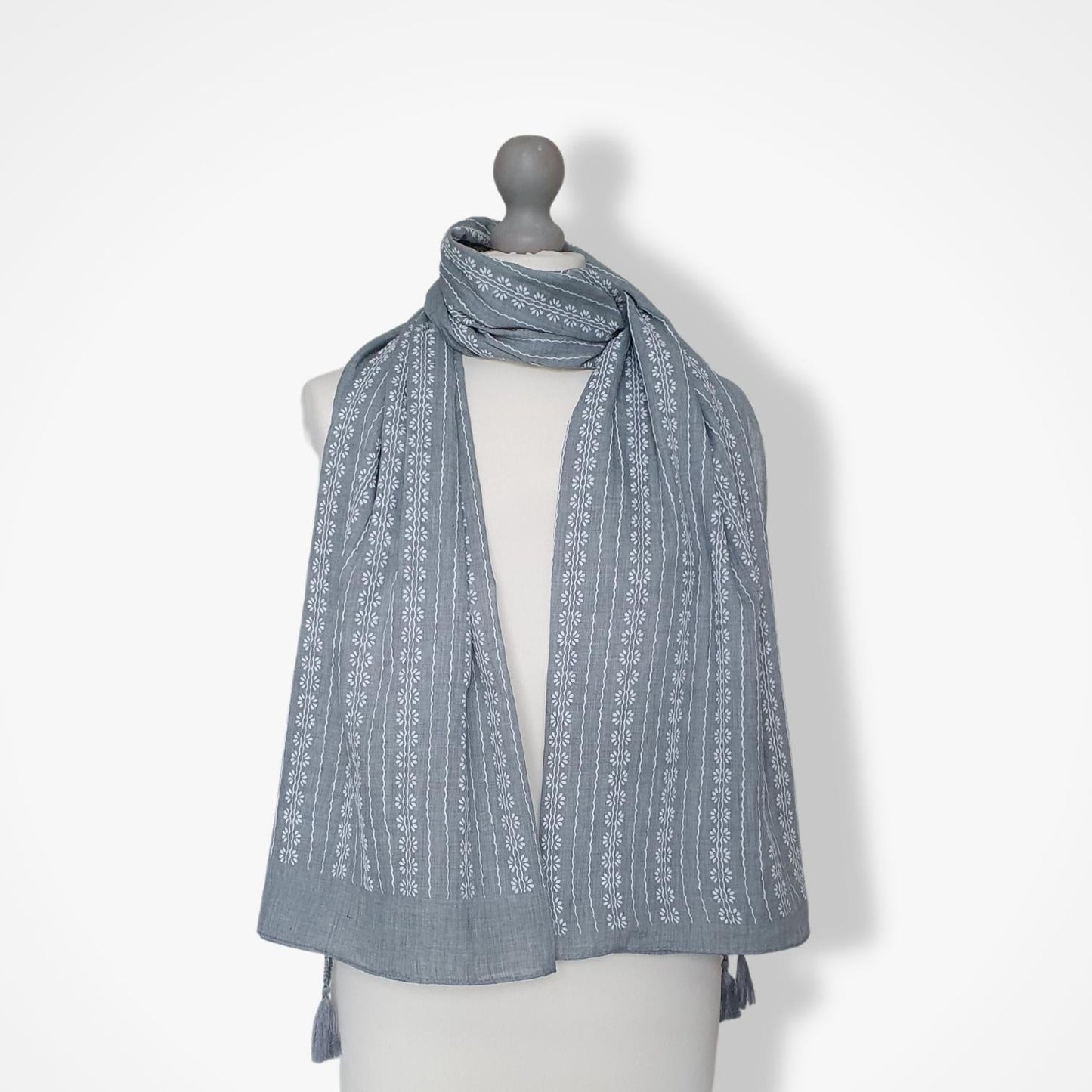 Gray patterned scarf on a mannequin against a white background