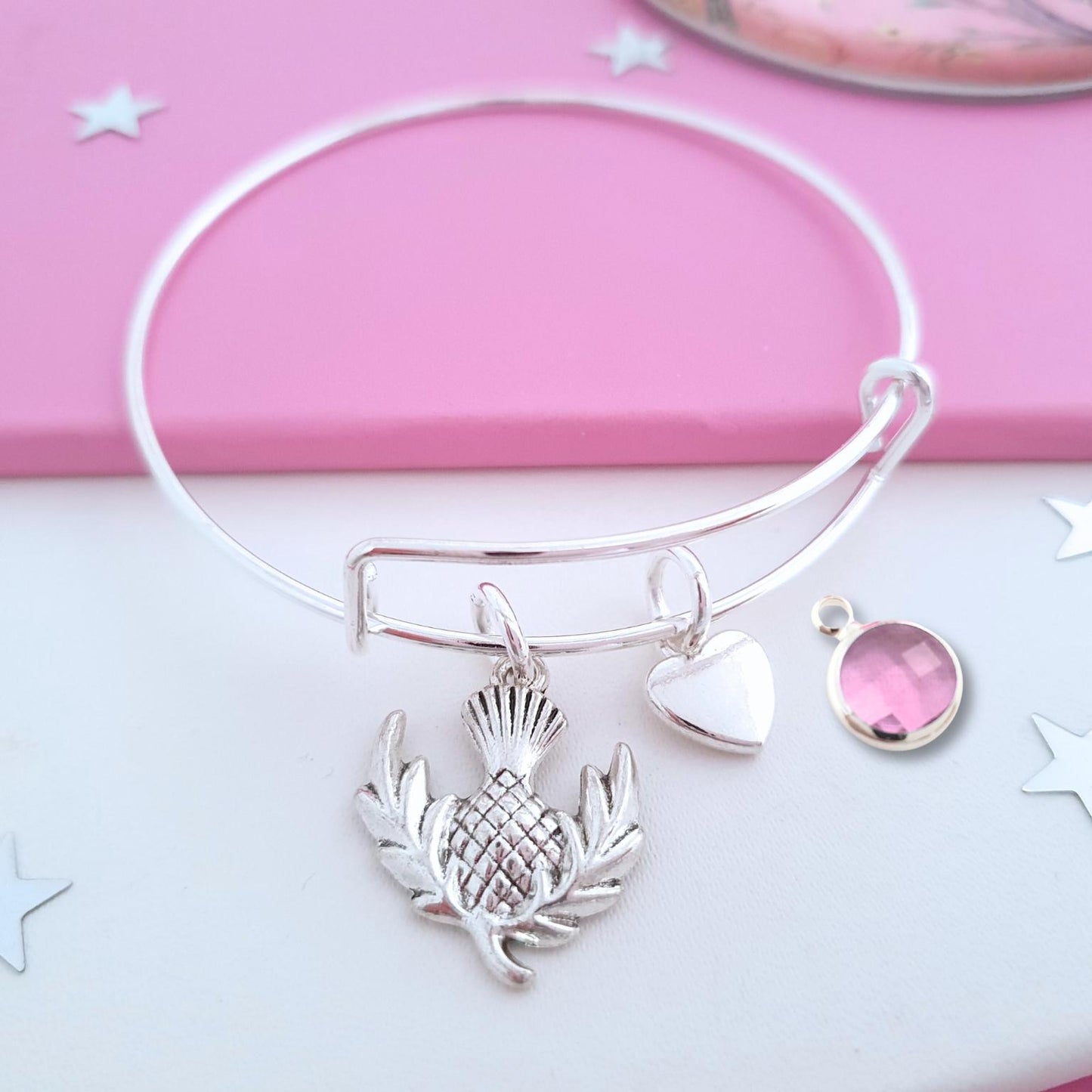 Silver bracelet with charms on a pink and white background