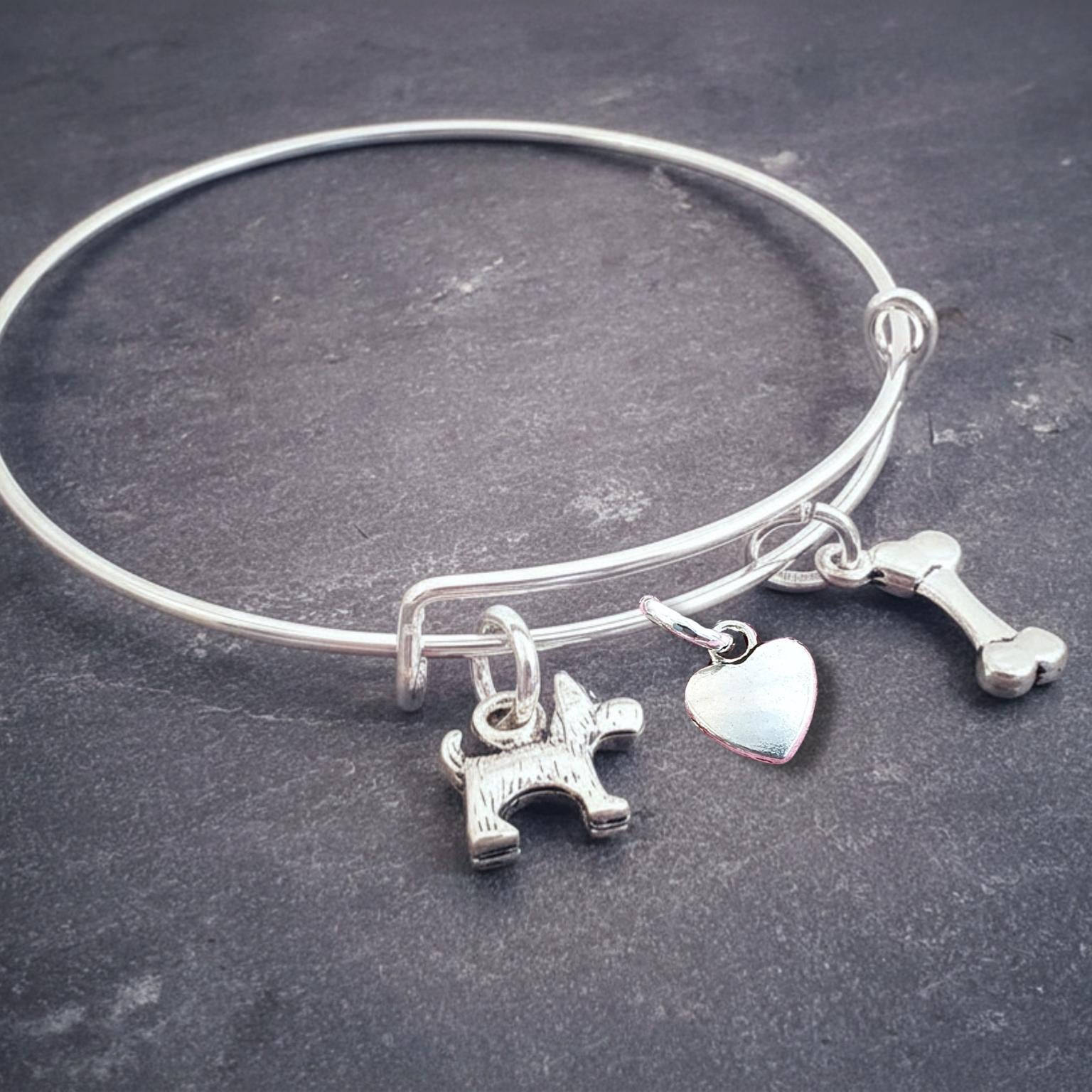 Silver bracelet with various scotty dog theme charms on a dark surface