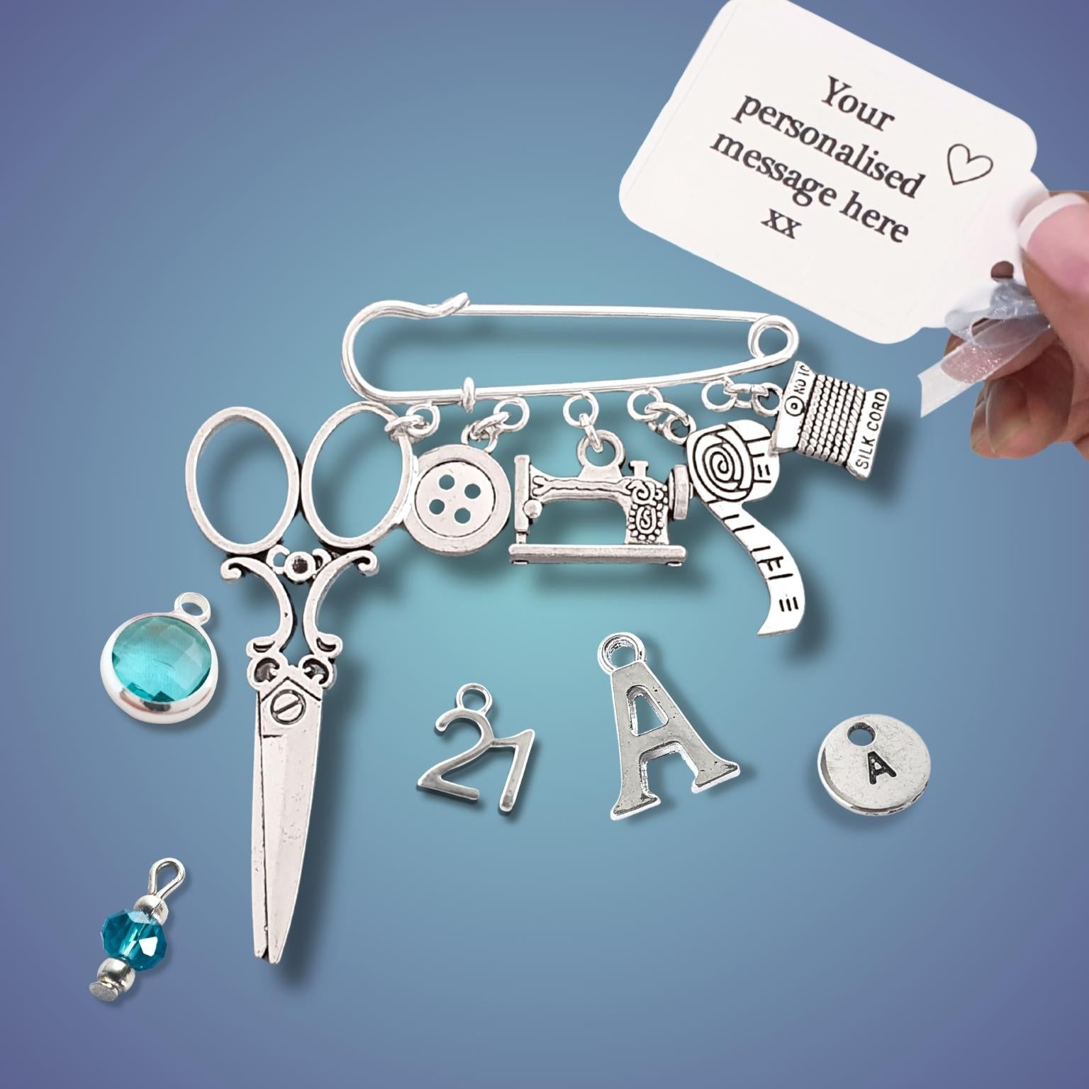 Brooch with sewing themed silver charms including scissors, sewing machine, buttons, with various charms on a blue background