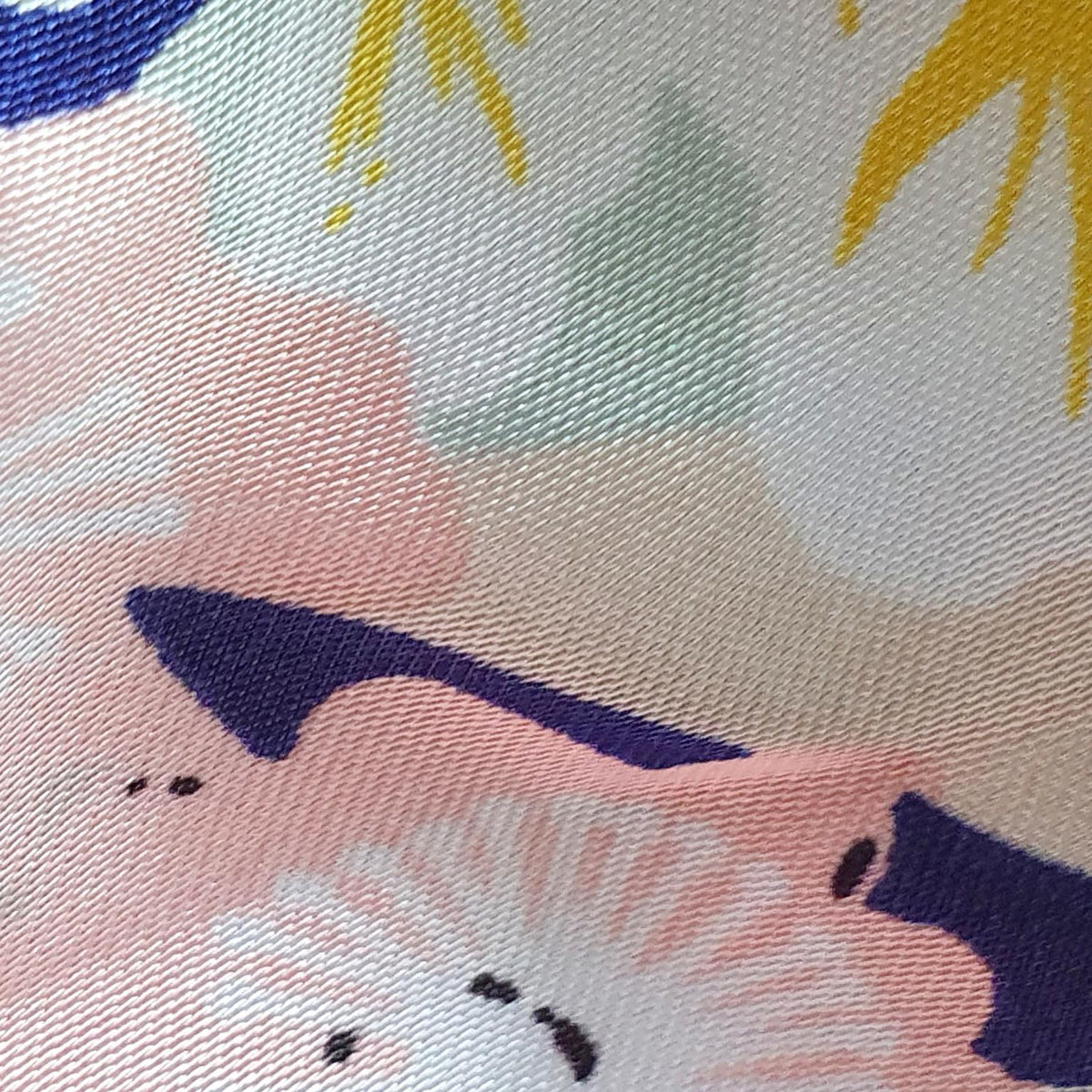 A close-up of a woven textile with a soft abstract floral pattern in pastel pink, cream, navy, yellow, and pale green.
