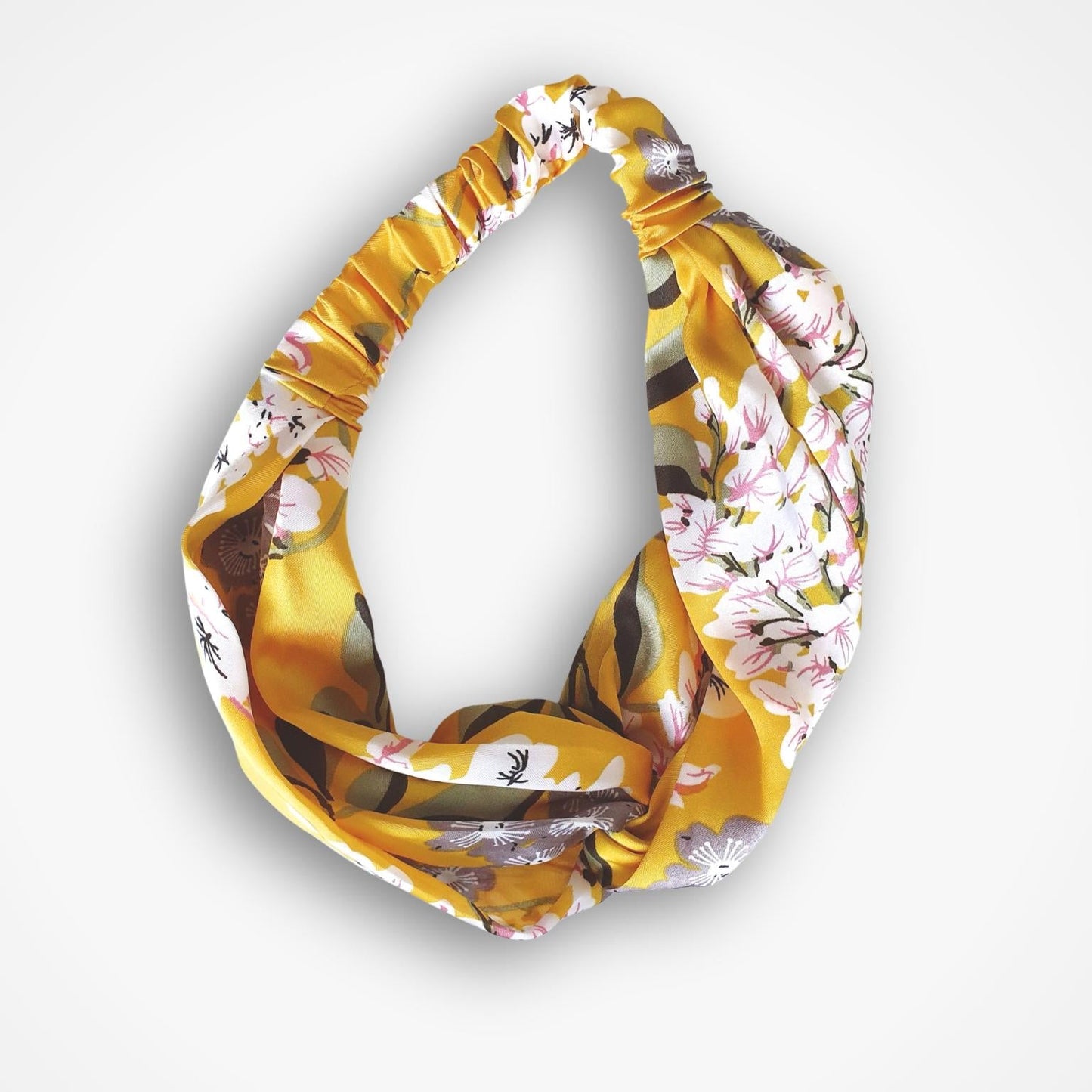 A knotted infinity headband featuring a yellow and white floral pattern with brown accents, displayed against a clean white background.