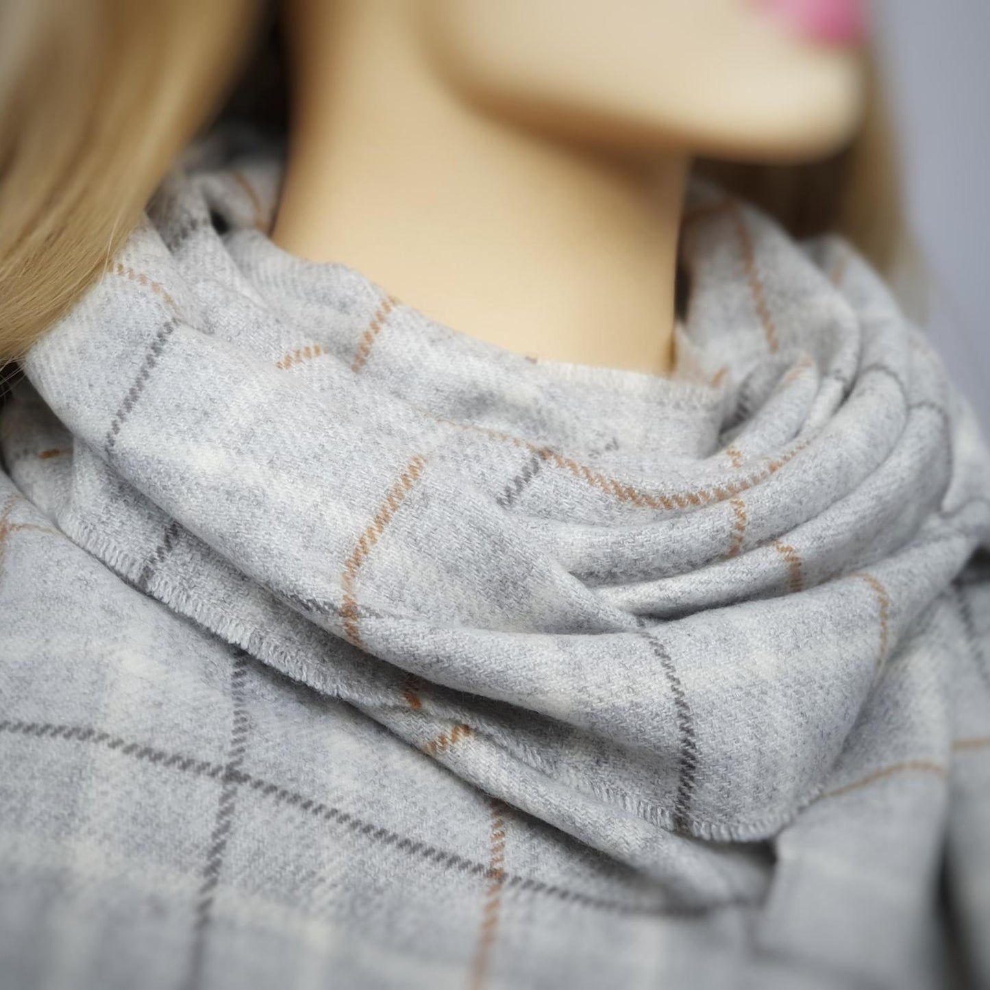 Mannequin wearing a gray plaid scarf with a blurred background