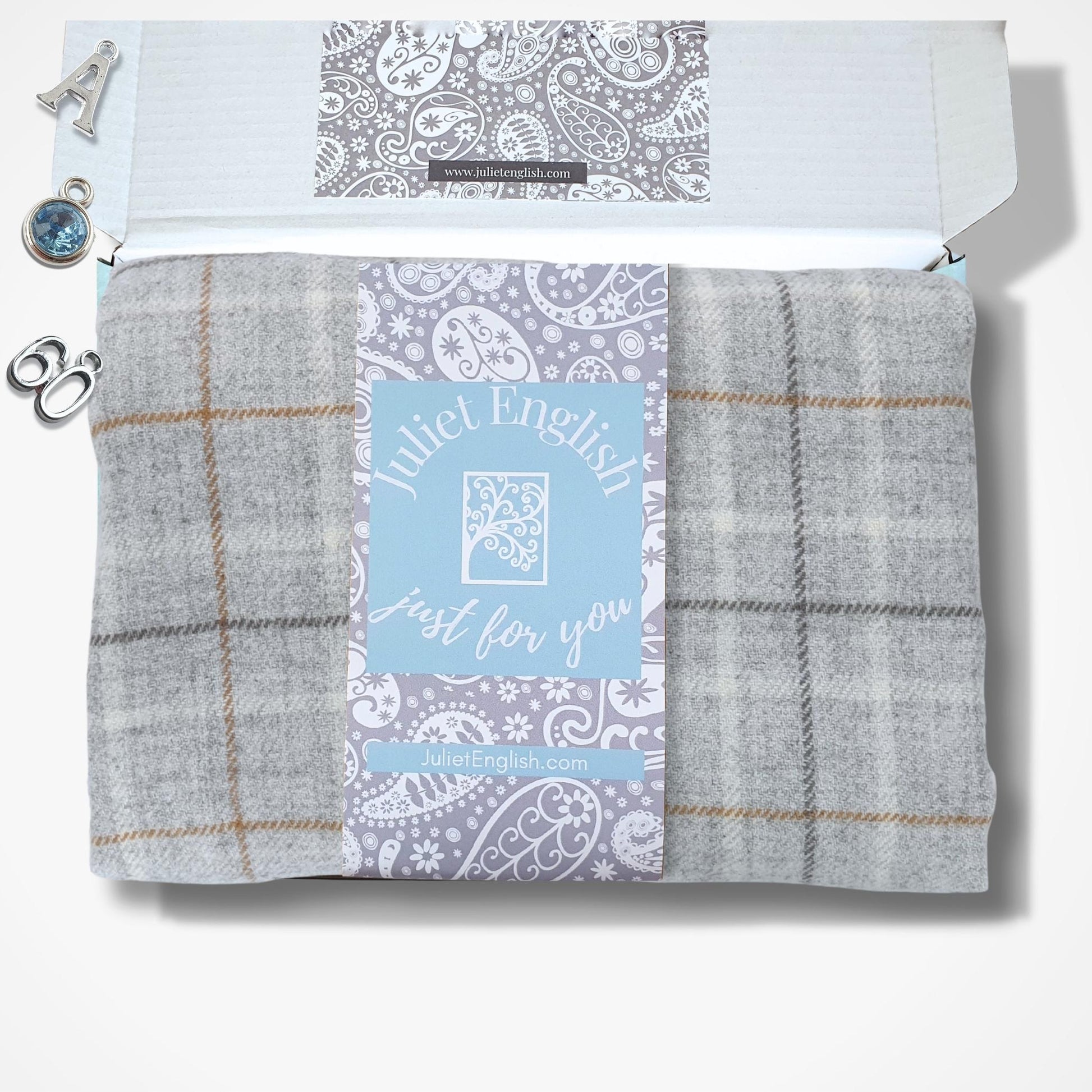 Folded scarf with plaid pattern and 'Juliet English' label in a box on a white background