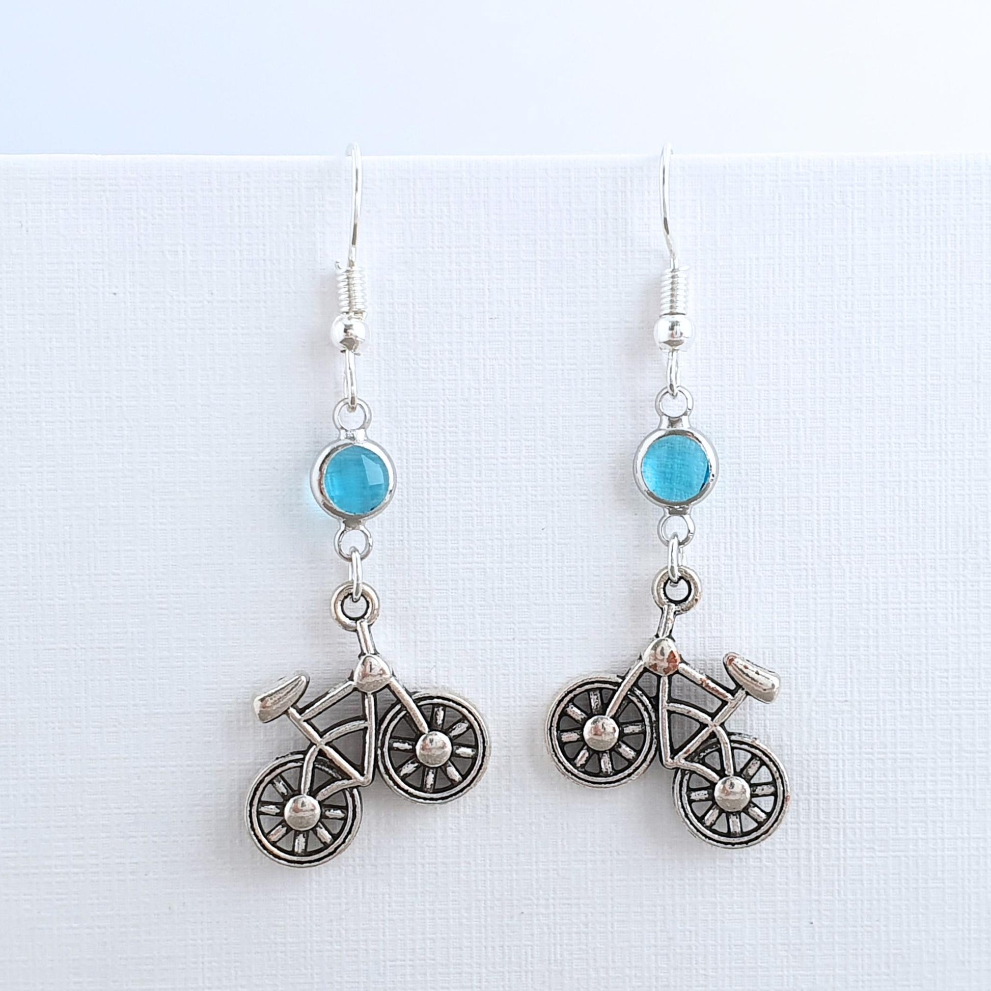 Bicycle-shaped earrings with turquoise stones on a white background