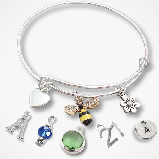 Silver bracelet with various charms including a bee, letter 'A', and heart on a white background