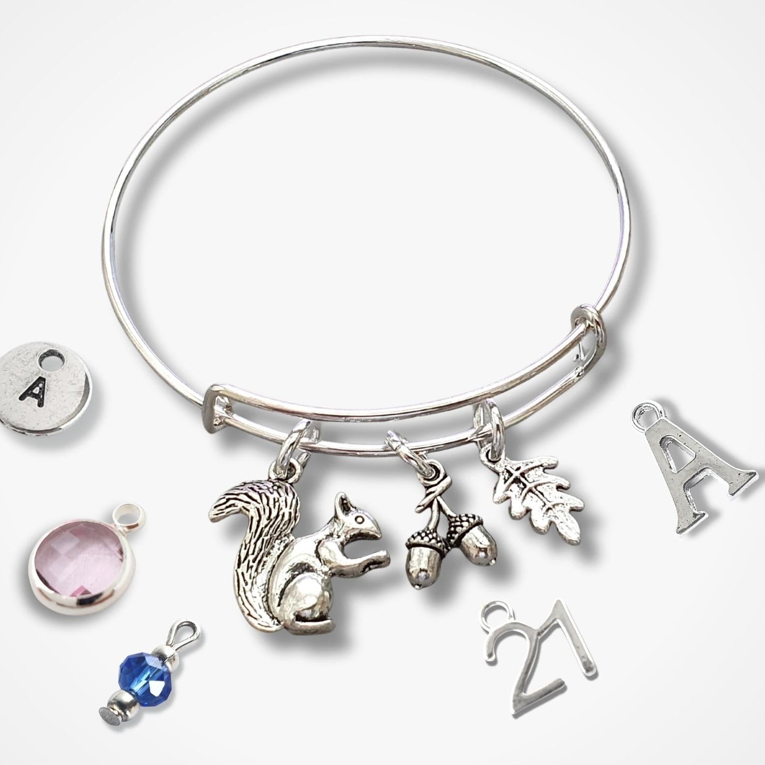 Silver bracelet with squirrel, acorn and leaf  charms on a white background