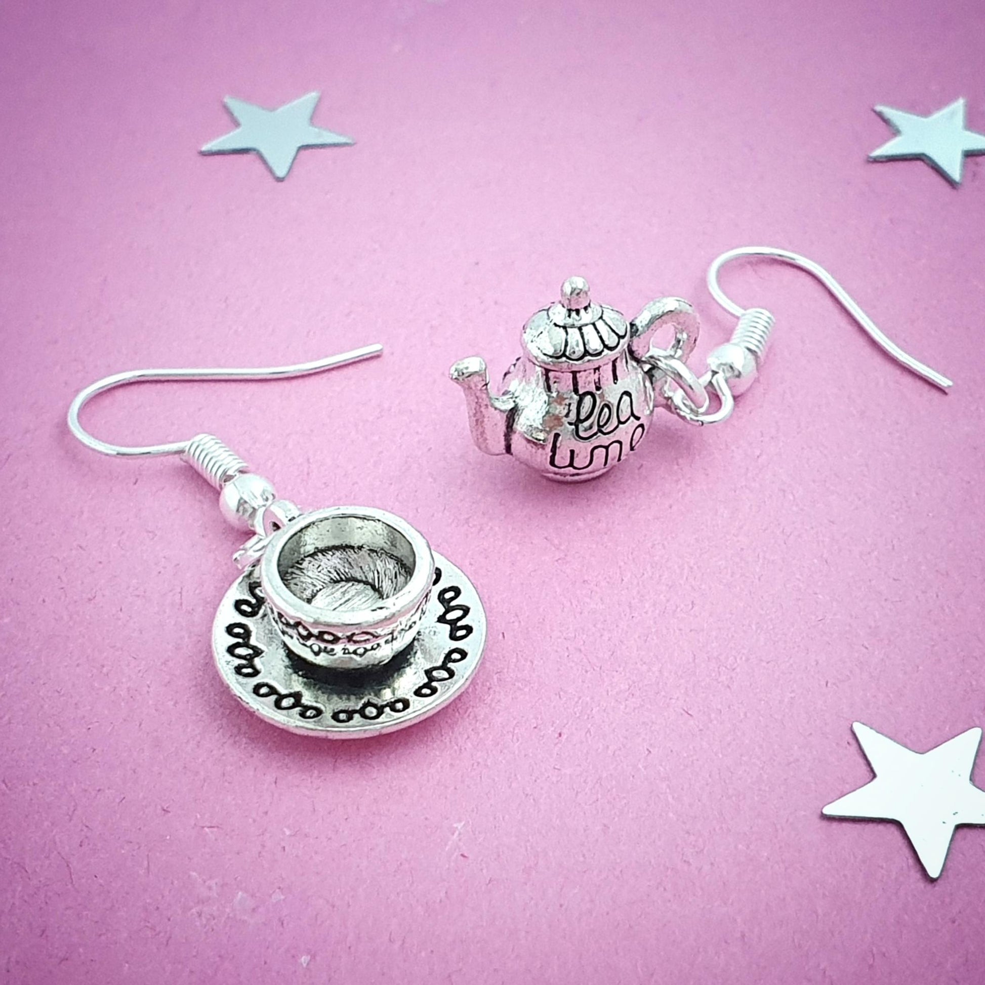 Tea cup and teapot earrings on a pink background with star decorations
