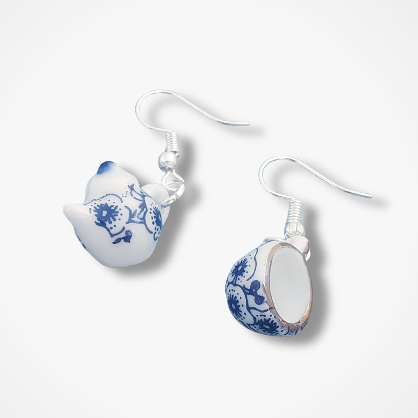 Pair of teapot and teacup earrings with blue floral patterns on a white background