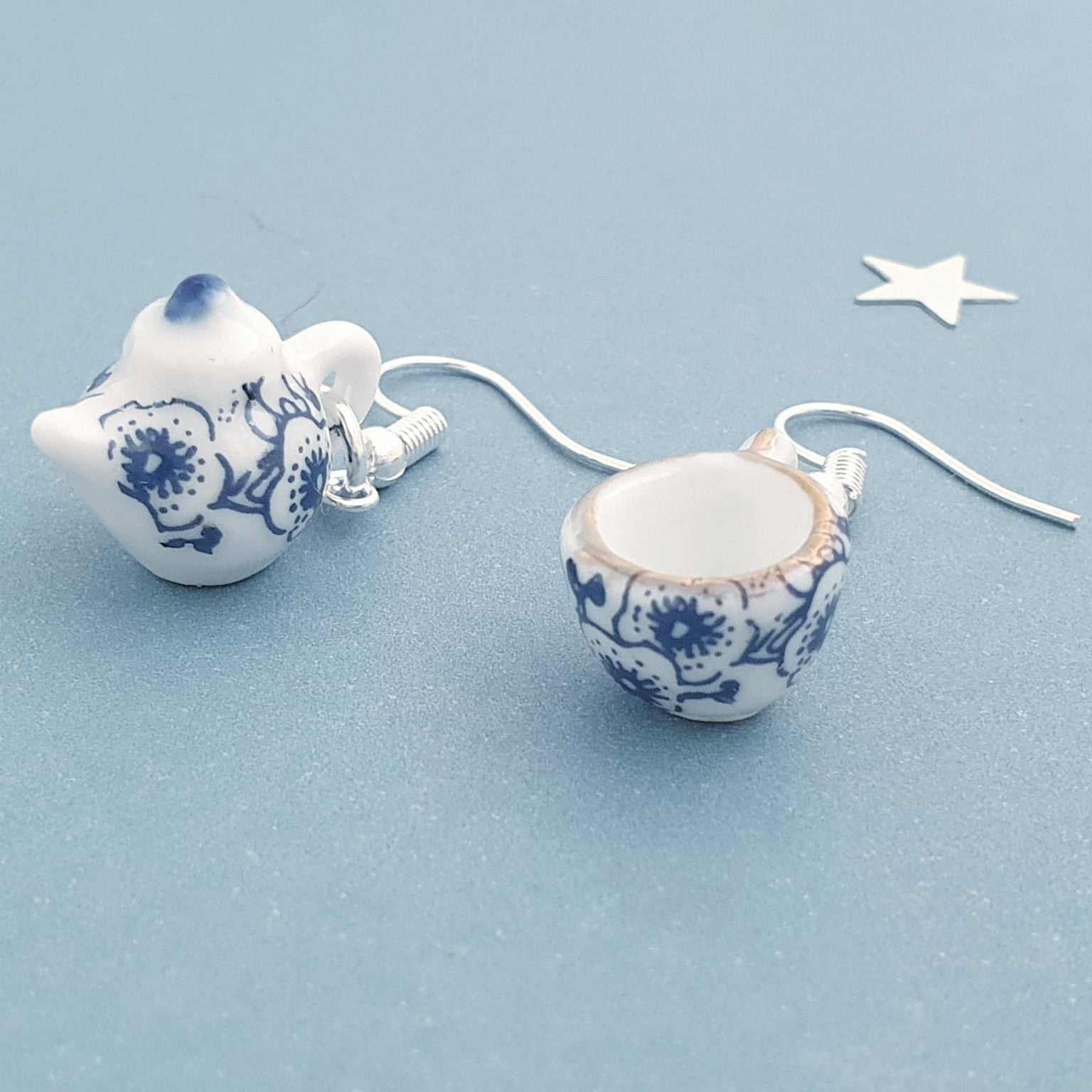 Pair of ceramic earrings with blue floral patterns on a light blue background.