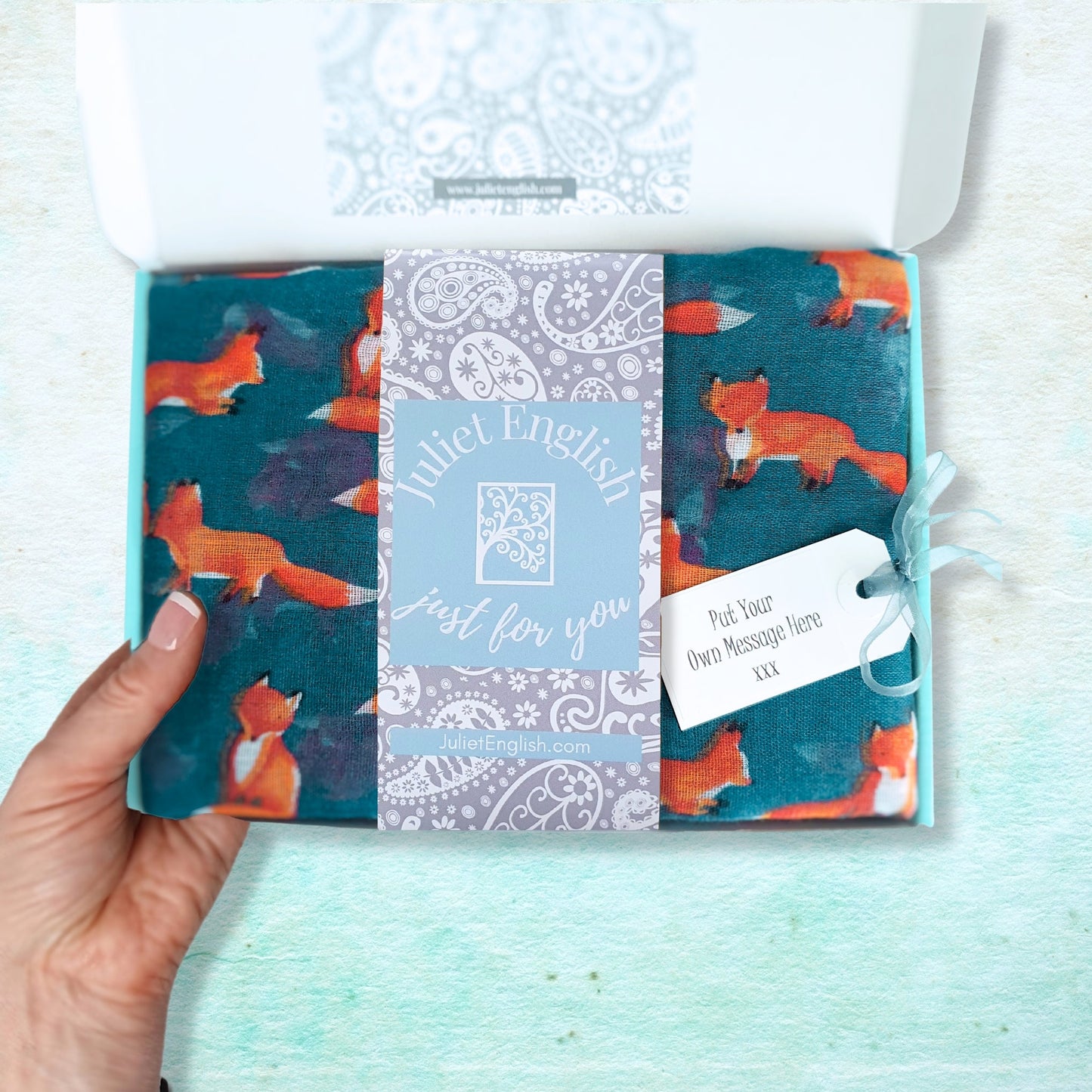 Packaged scarf with fox design on a light blue background