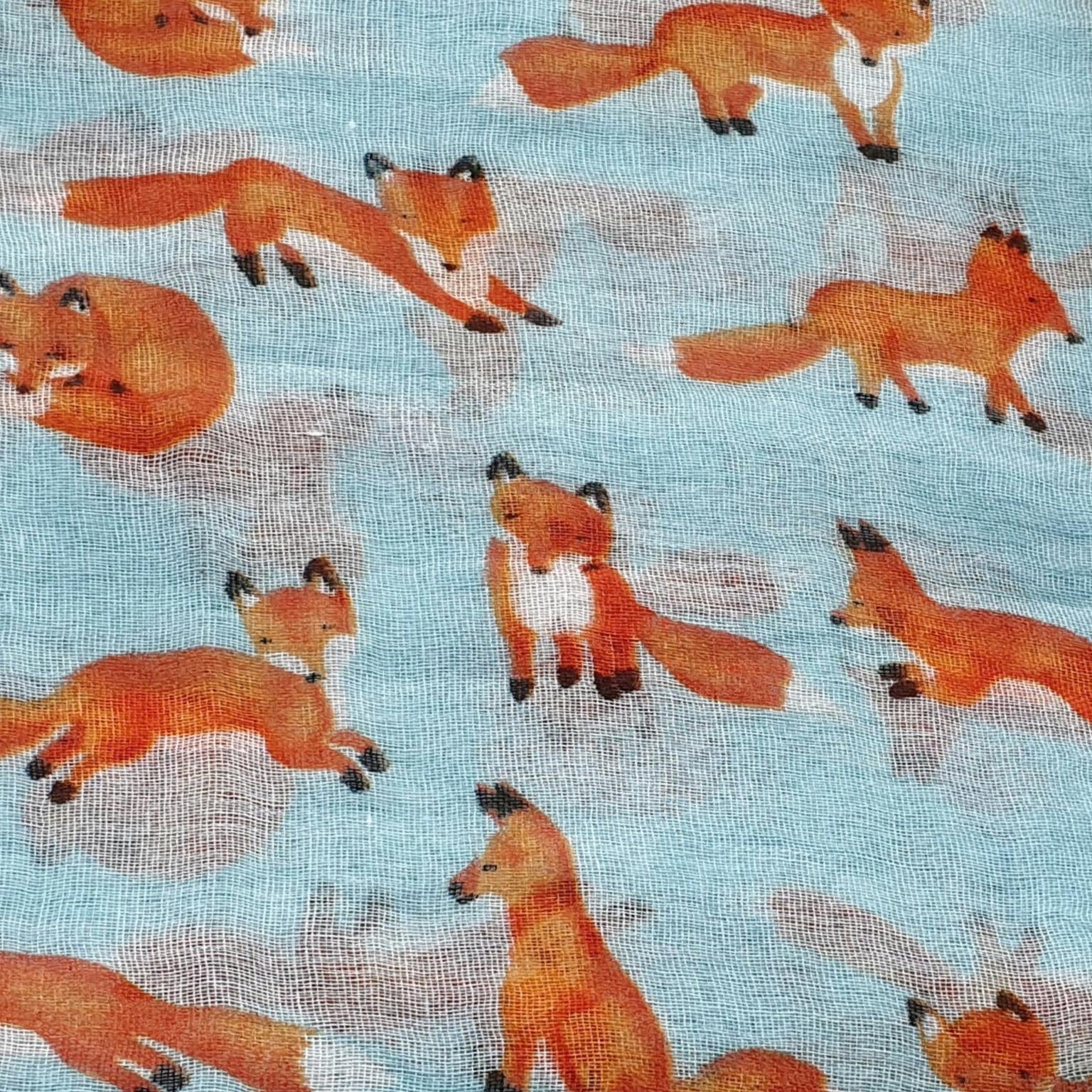 Light blue scarf with a repeating pattern of orange foxes in various poses, including sitting, standing, and lying down.