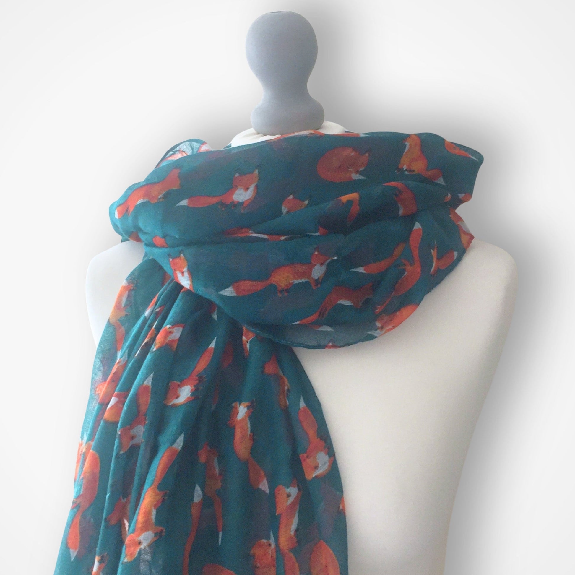 Teal scarf with fox pattern draped over a mannequin against a white background