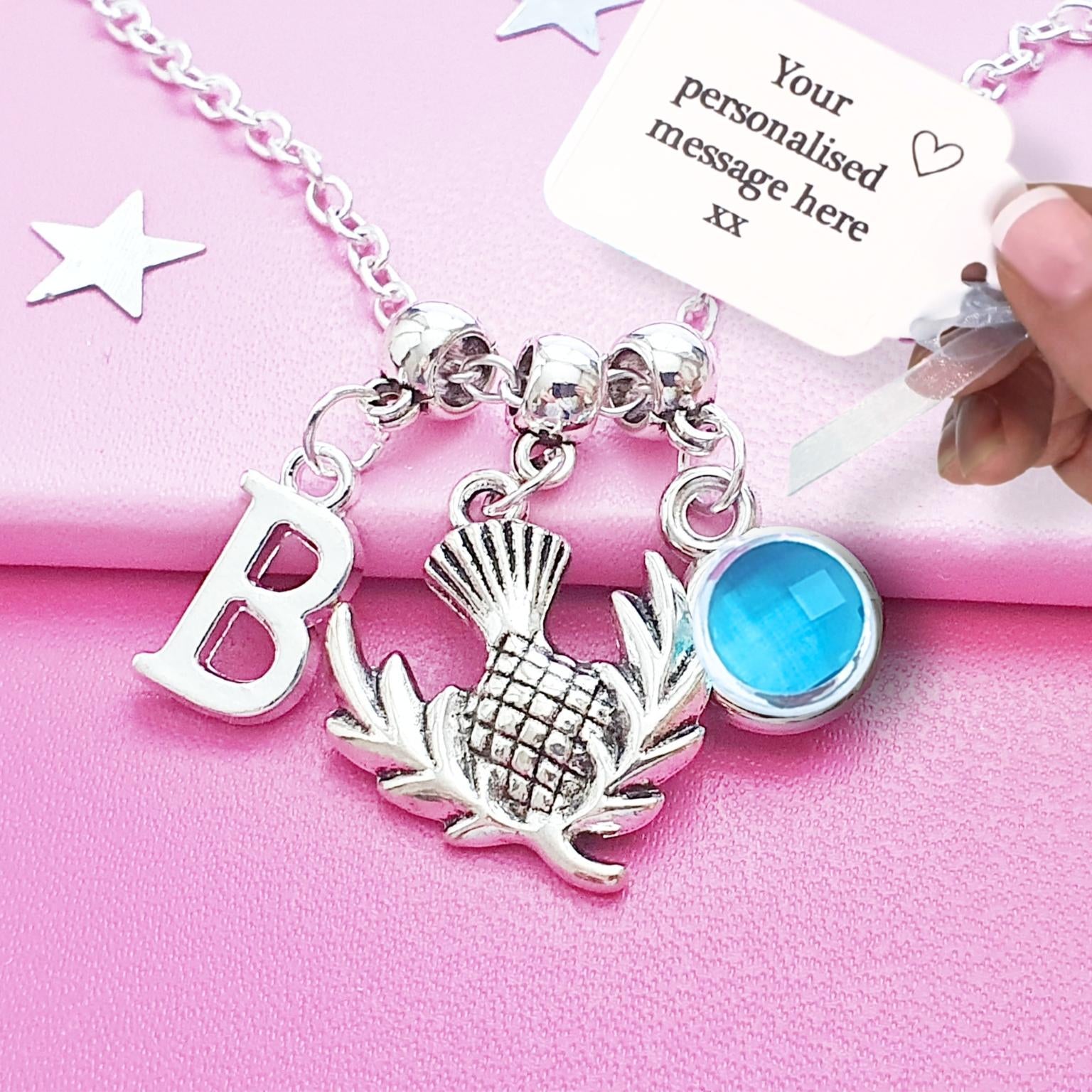 Silver necklace with charms on a pink background