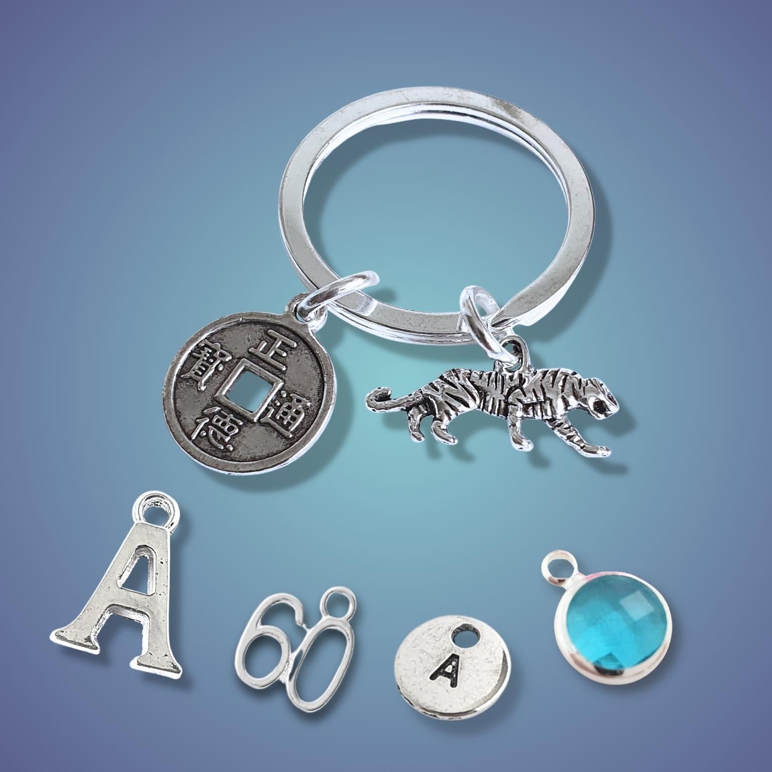 Silver keychain with tiger charm and coin charm on a gradient blue background