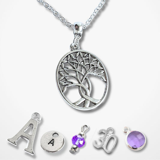 A silver Tree of Life pendant necklace displayed with five matching customizable charm options below it on a light gray background. The main pendant features a detailed tree design inside a circle, while the options below include a letter 'A', a letter 'A' with a gem, a purple gem charm, a '30' charm, and a purple gem bezel.