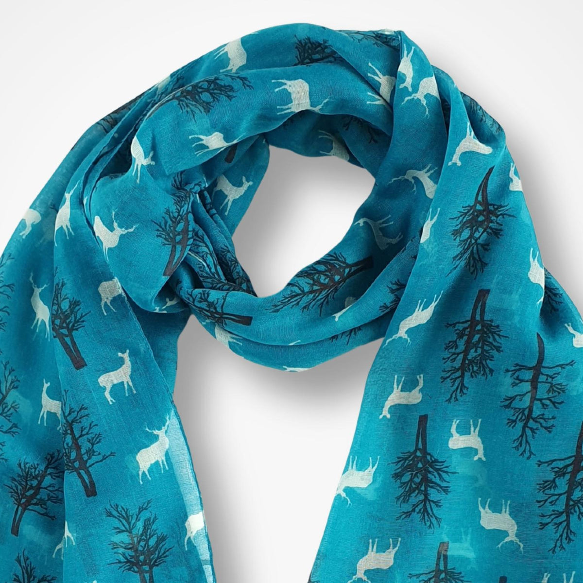 A teal blue scarf with a repeating pattern of white deer and black tree silhouettes, draped in a loop against a light gray background.