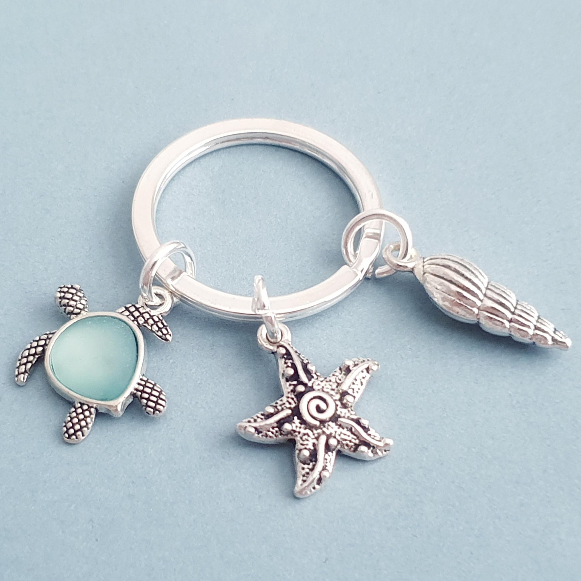 Keychain with turtle, starfish, and shell charm on a light blue background