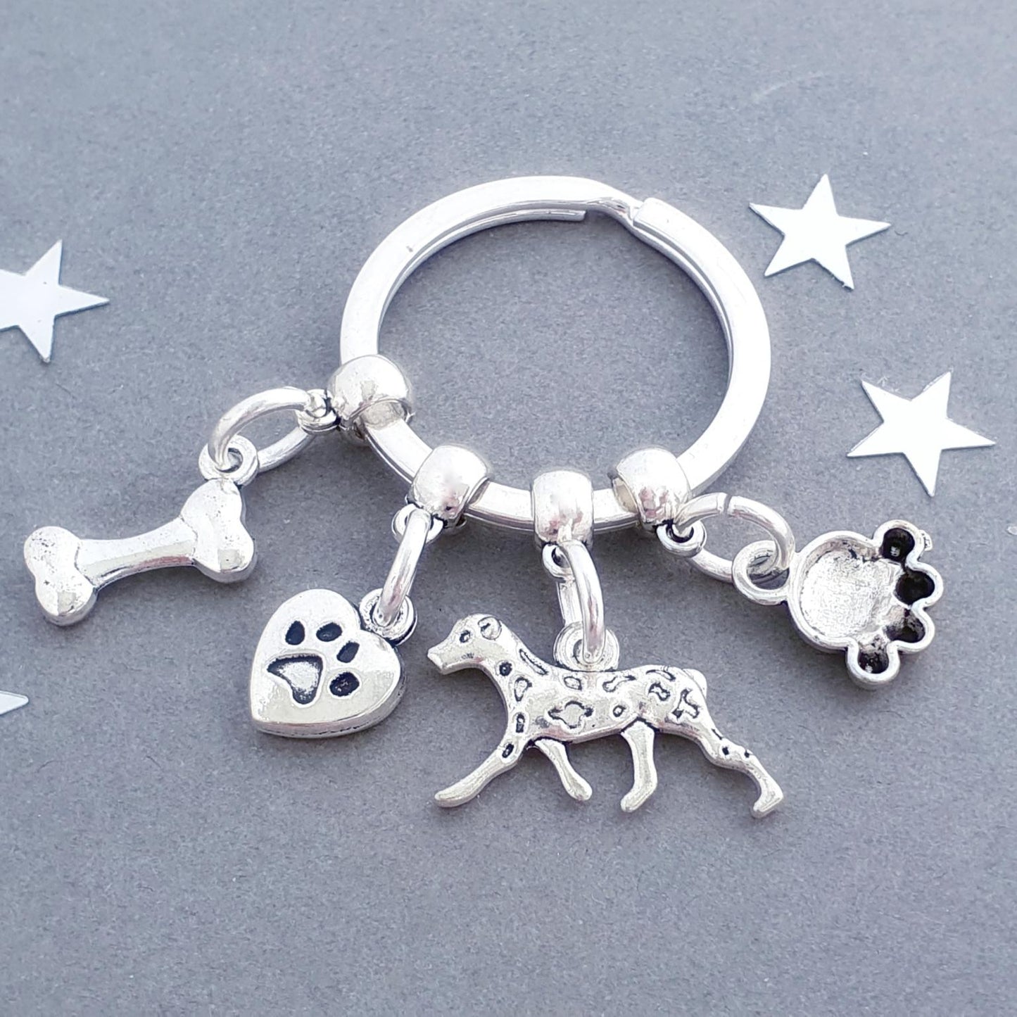 Silver keychain with dog-themed charms on a gray background with star decorations