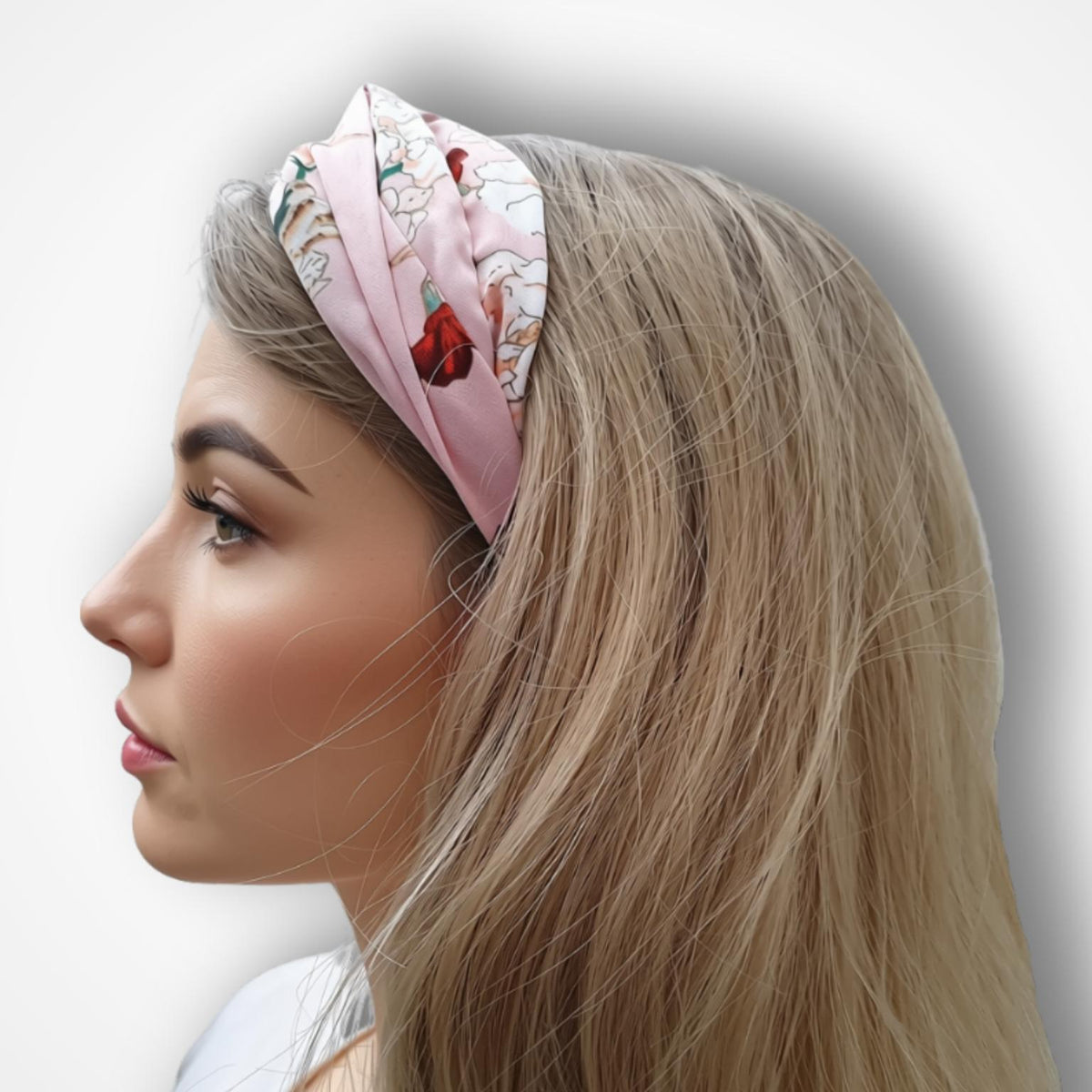 A woman in profile wearing a light pink fabric headband with a delicate floral pattern, set against a plain light gray background.