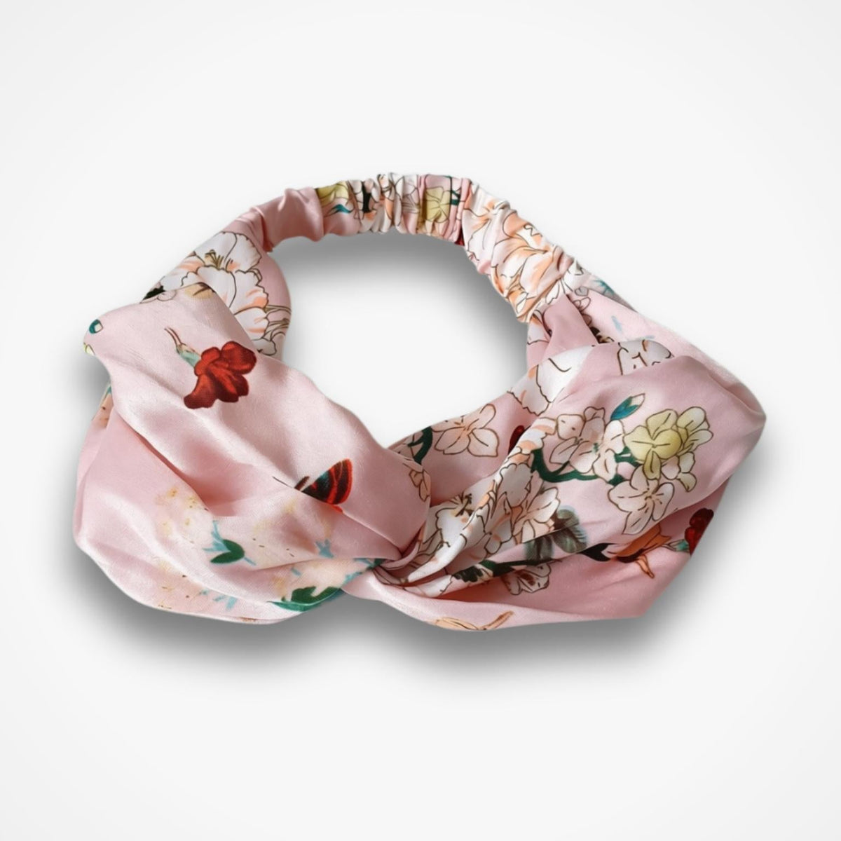 A pink satin knotted headband with a delicate floral and butterfly print, displayed on a clean white background.