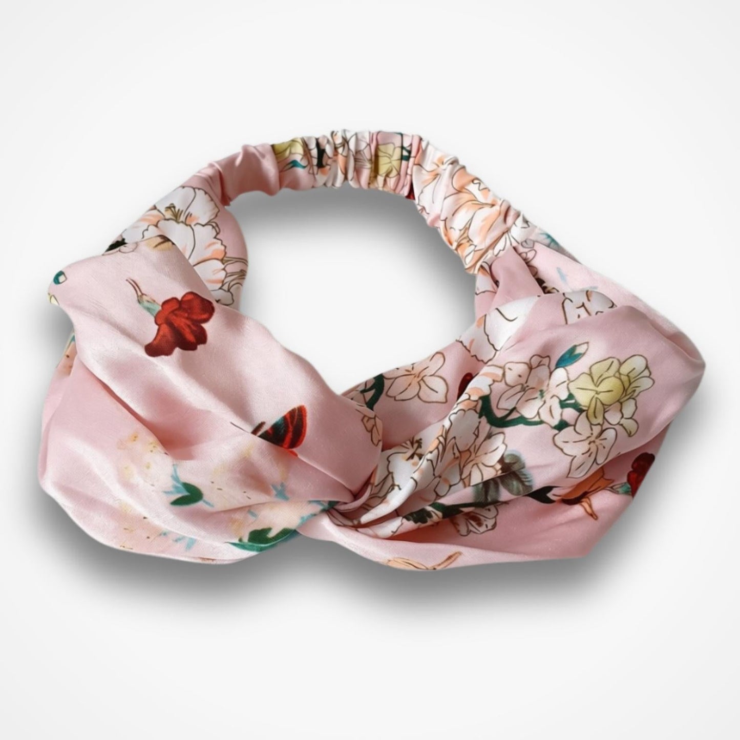 A pink knotted headband with a delicate floral and butterfly pattern, displayed on a clean white background.