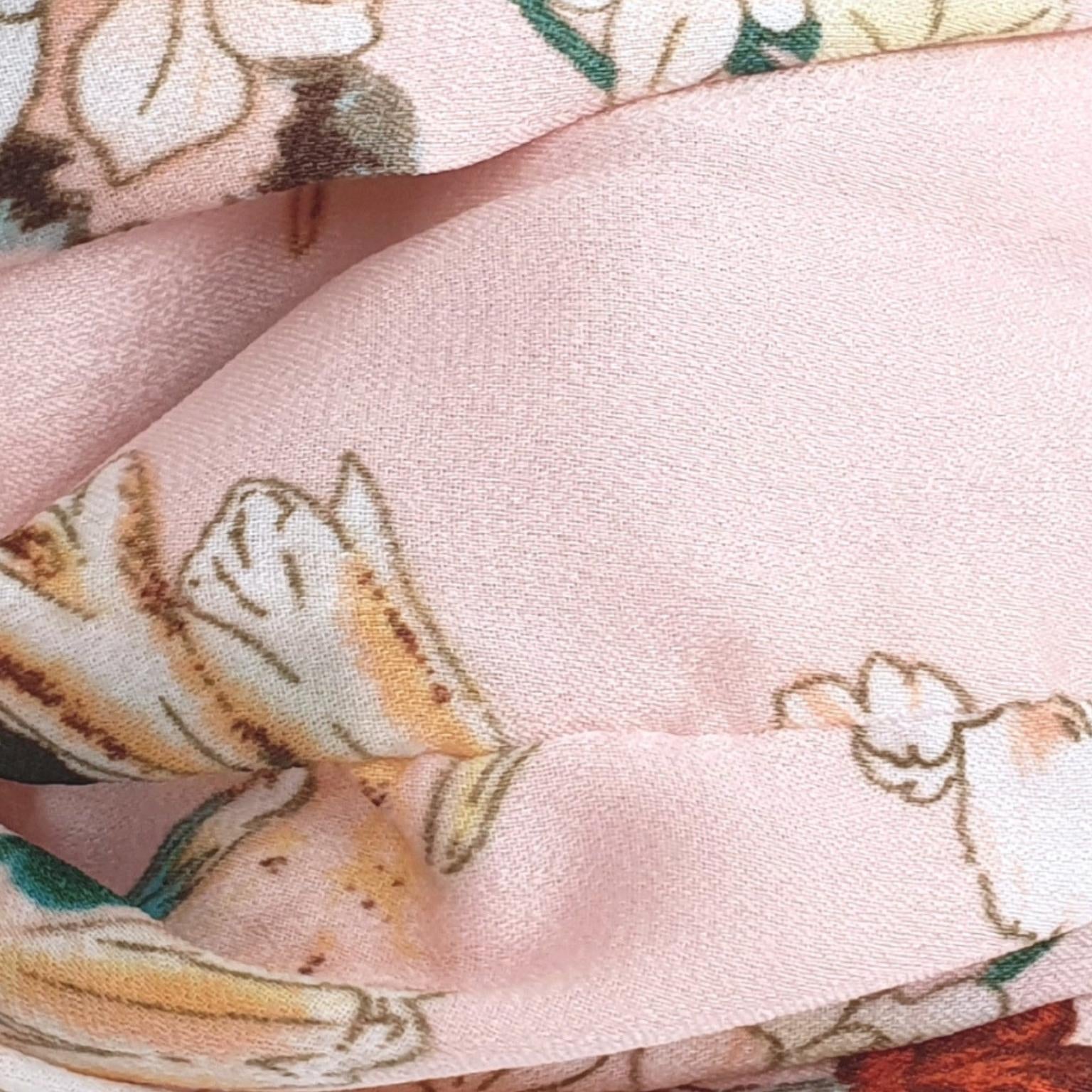 A close-up of a light pink fabric with a delicate floral print in cream, beige, and soft green.