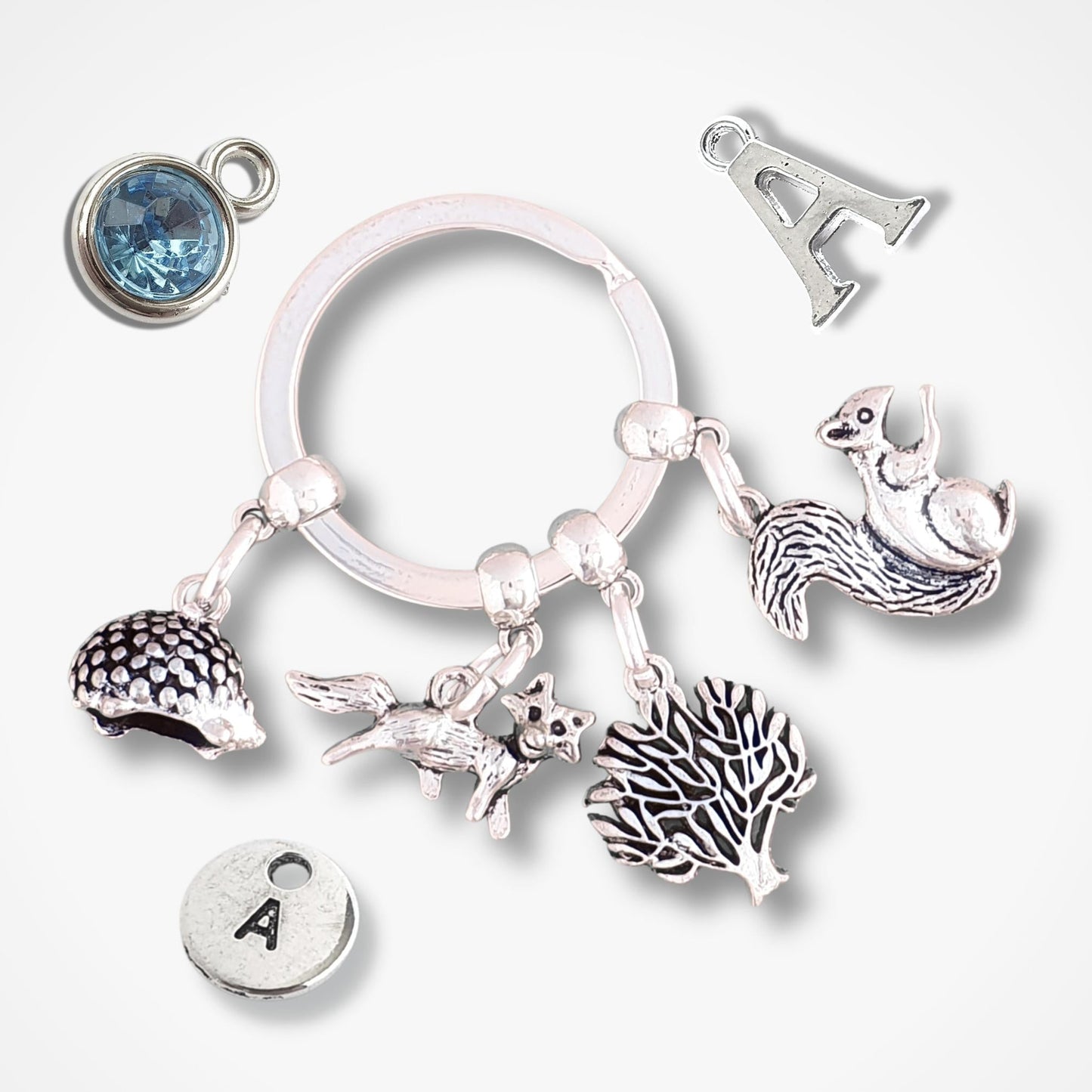 Silver keychain with hedgehog, fox, tree and squirrel charms on a white background