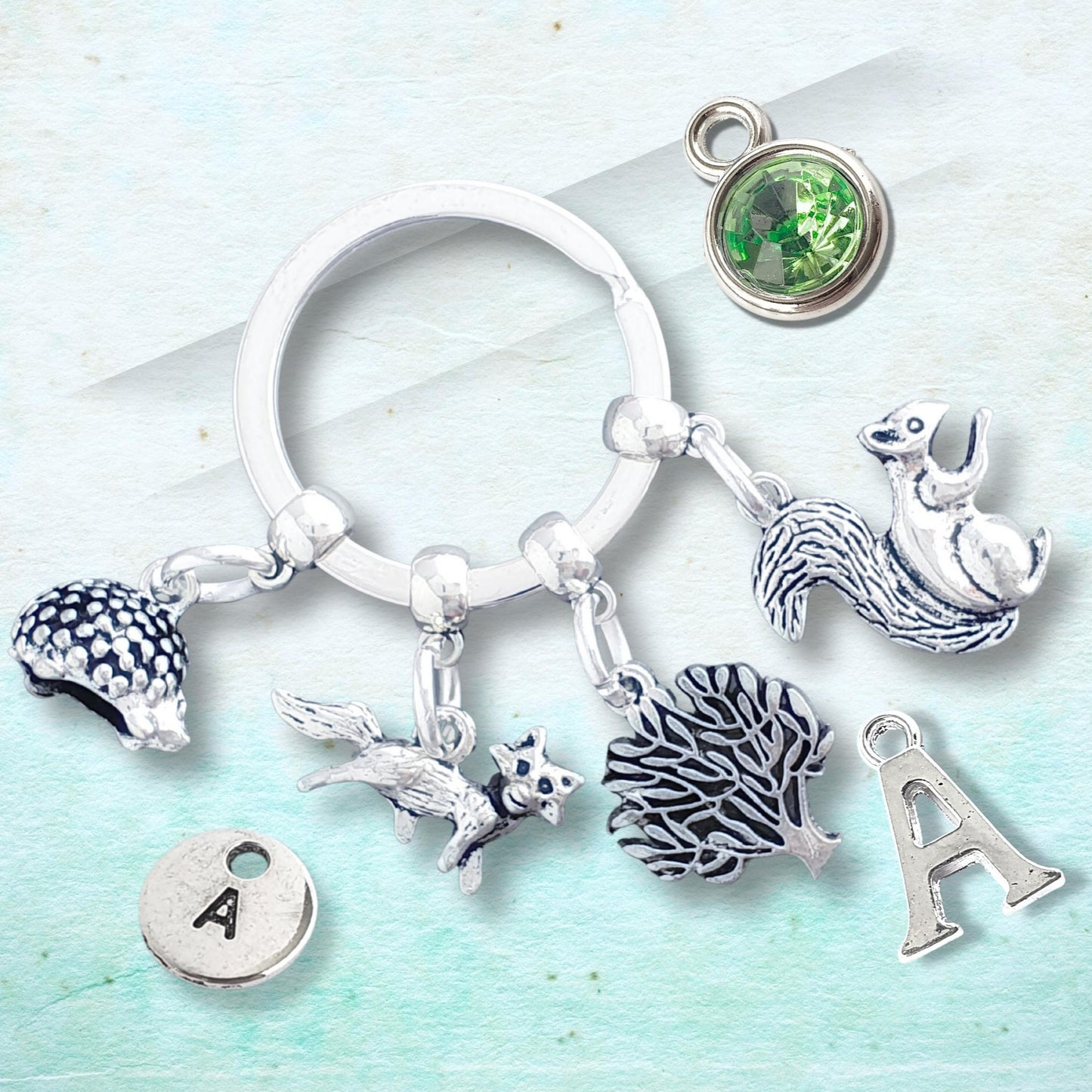 Keychain with hedgehog, fox, tree and squirrel charms on a light blue background