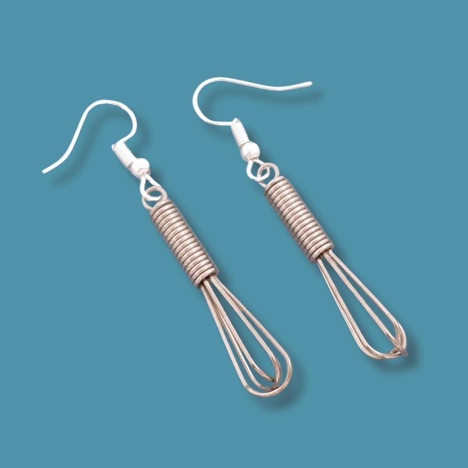 Pair of whisk-shaped earrings on a blue background