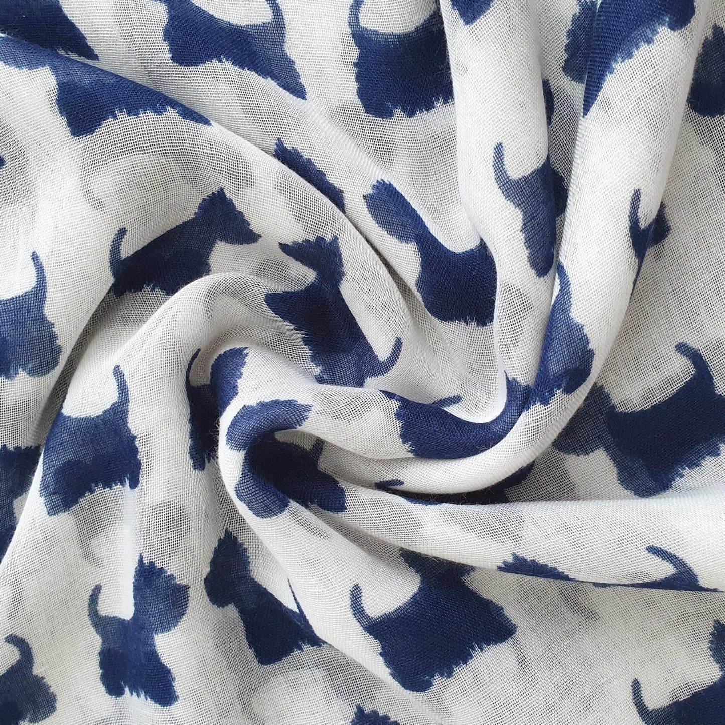 White lightweight scarf with a repeating navy blue dog silhouette print, shown in a styled swirl drape.