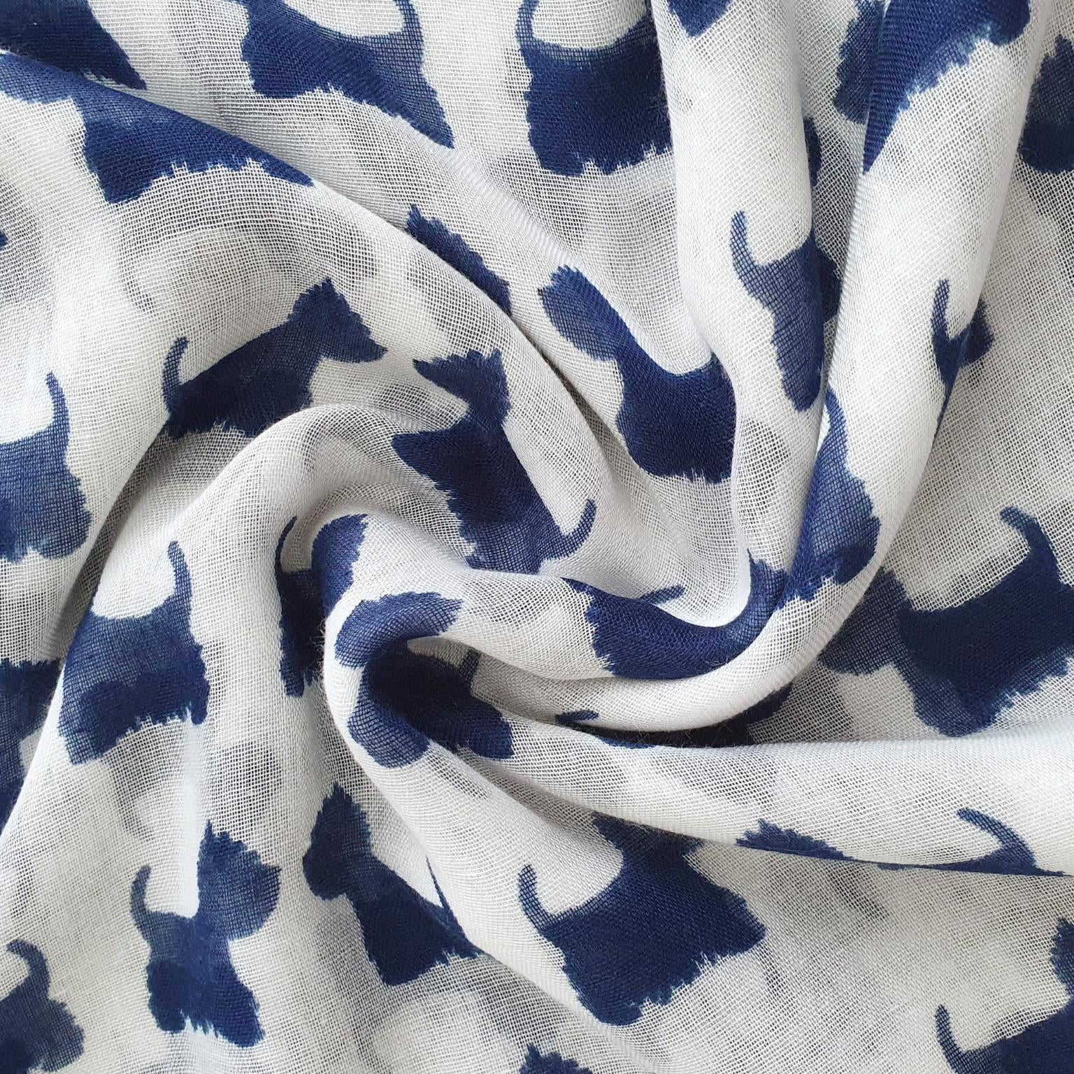 White lightweight scarf with a repeating navy blue dog silhouette print, shown in a styled swirl drape.